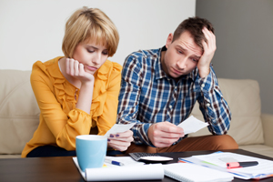 Couple sitting at table frustrated with paying bills